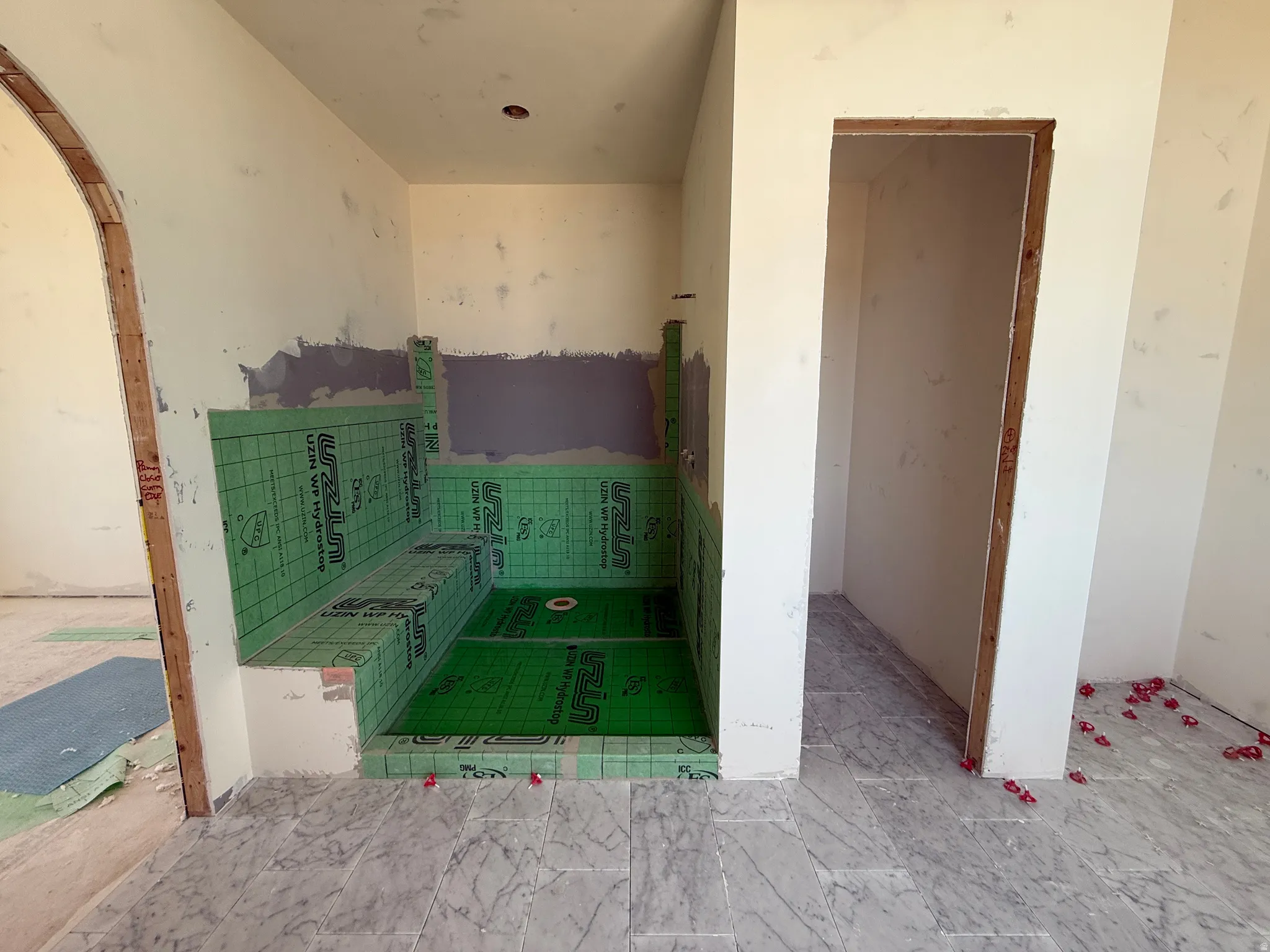 Bathroom under construction featuring a built-in shower bench, recessed shower niche, and a shower pan ready for tiling