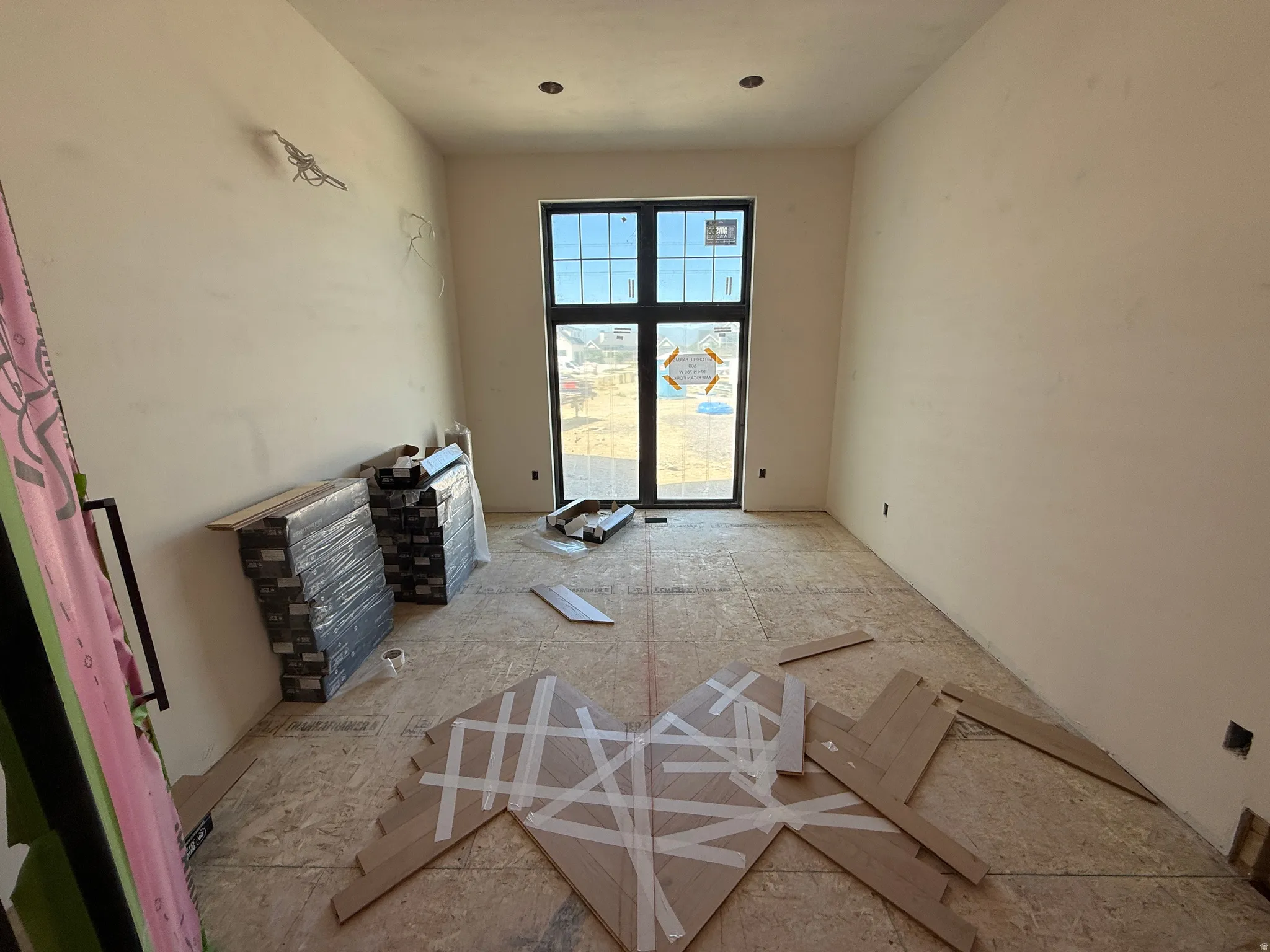 Spacious room featuring a full-height window with dark framing and grid-pane design, recessed ceiling lighting, and light-toned wall finishes