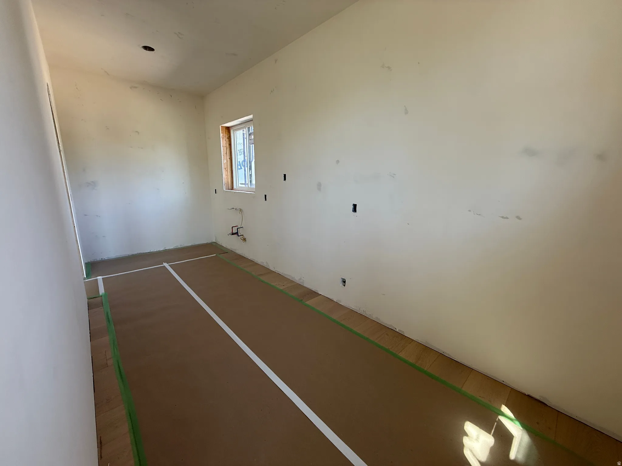 Room featuring a window, light-toned walls, and wood-finish flooring