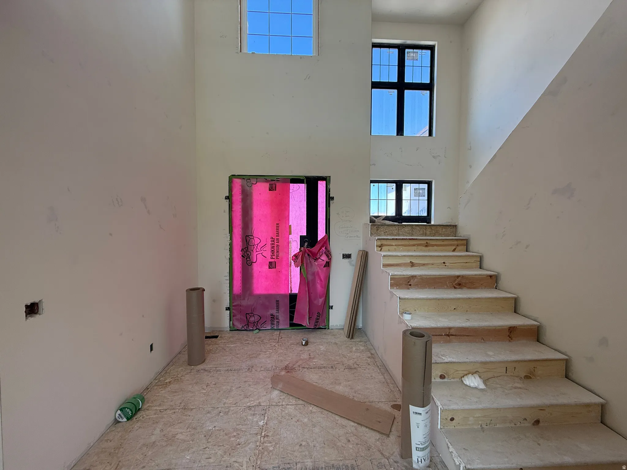 Grand entry with high ceilings, multiple transom windows, an abundance of natural light, and an unfinished staircase awaiting custom finishes