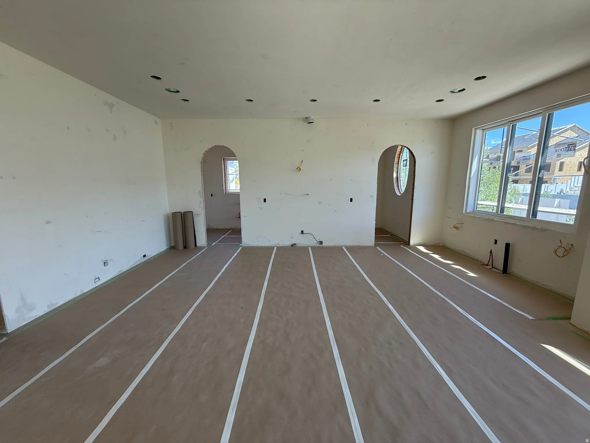 Spacious interior featuring multiple arched doorways, large windows providing abundant natural light, and recessed ceiling lighting