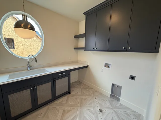 Round window with pendant lighting, integrated sink, wood-finish flooring, and built-in cabinetry