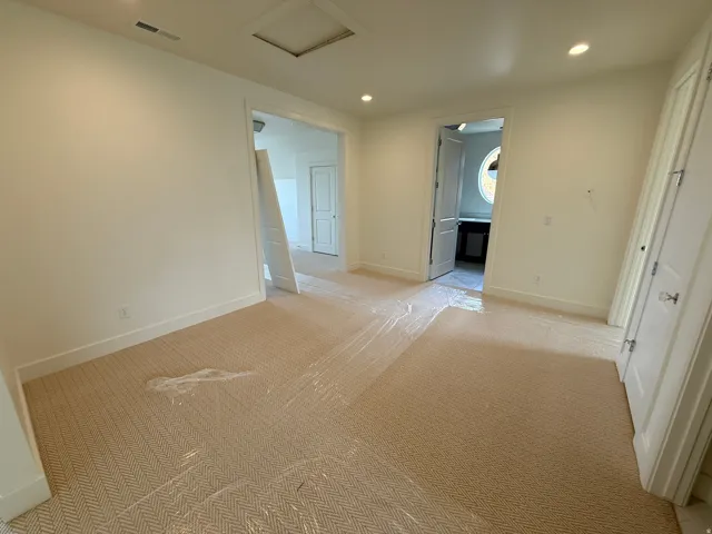 Recessed ceiling lighting, light-toned wall finishes, and patterned carpeting