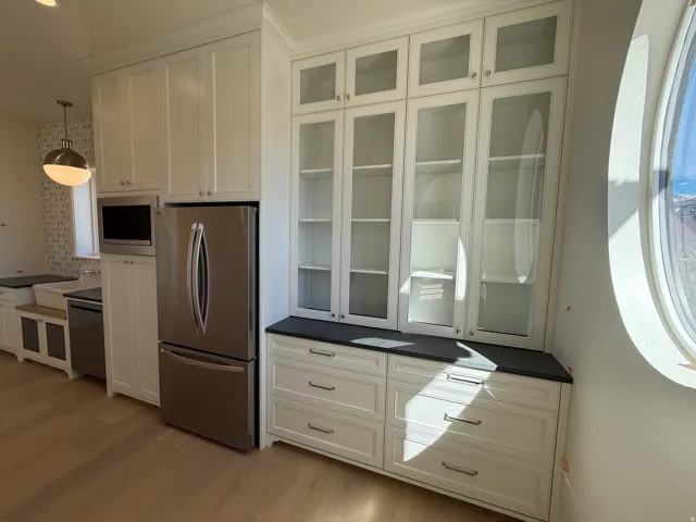 White shaker cabinetry, stainless steel appliances, wood-finish flooring, and a spherical pendant light fixture