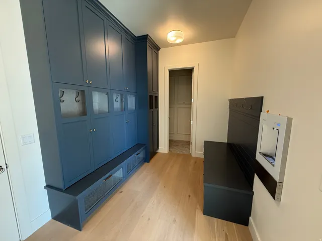 Built-in cabinetry with shaker-style doors, glass-front compartments, and integrated hooks