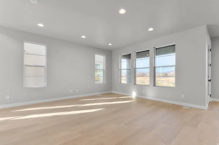 Spacious room featuring light-toned wood-finish flooring and recessed lighting