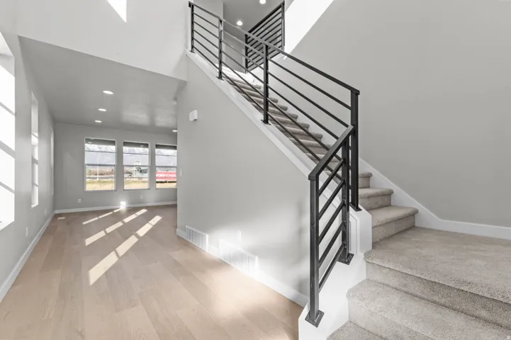 Two-story entryway featuring a modern staircase with black horizontal railings and light gray carpeting