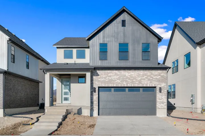 Modern two-story residence featuring a multi-textured facade with light grey brick, vertical dark grey siding, and smooth light stucco