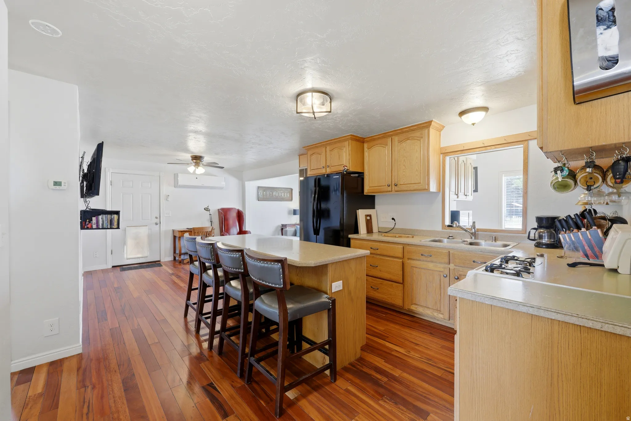 Kitchen featuring wood-finish flooring, light wood cabinetry, a double basin sink, and a black appliance package