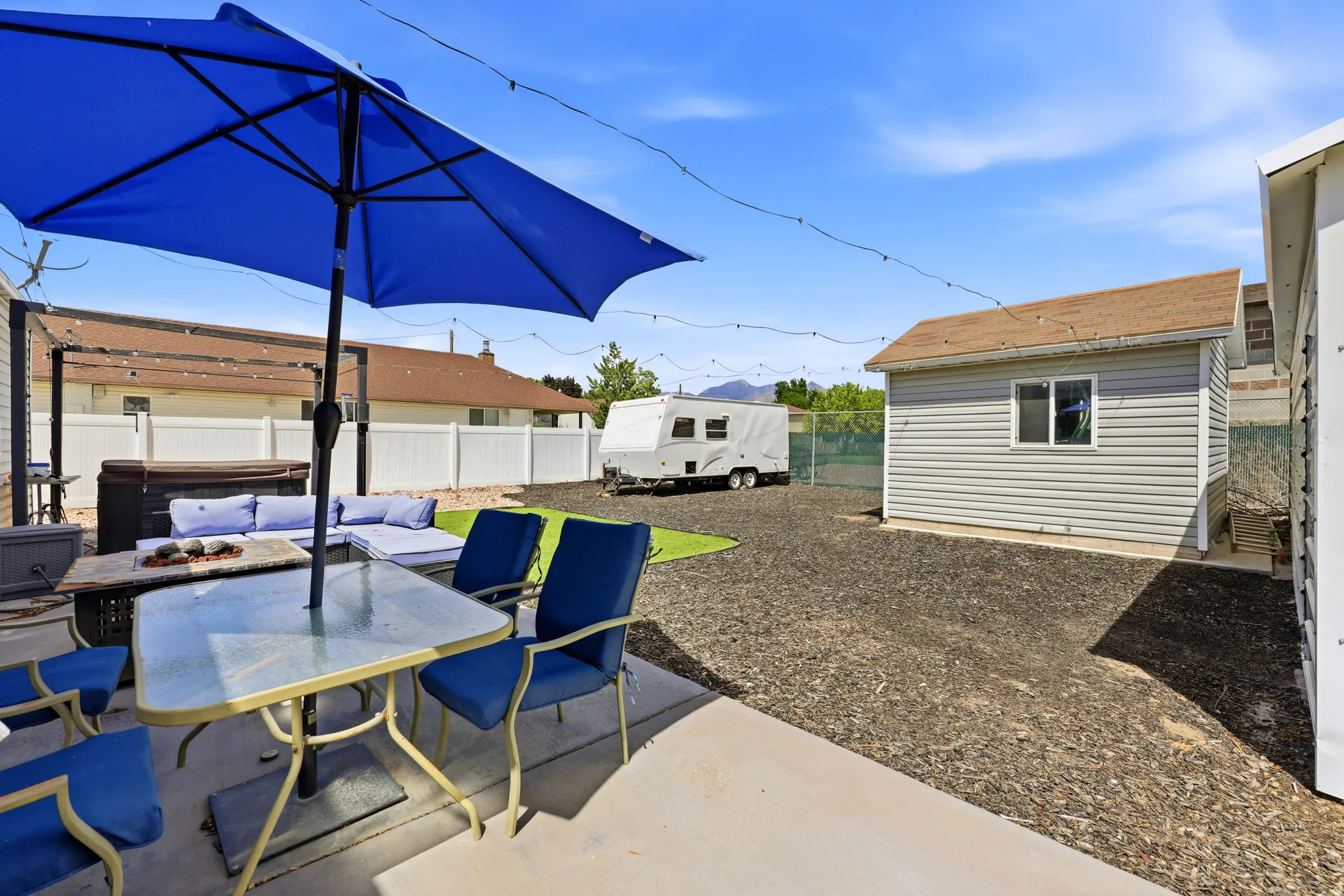 Patio area featuring concrete surfacing, a hot tub, string lighting, and a detached shed with horizontal siding