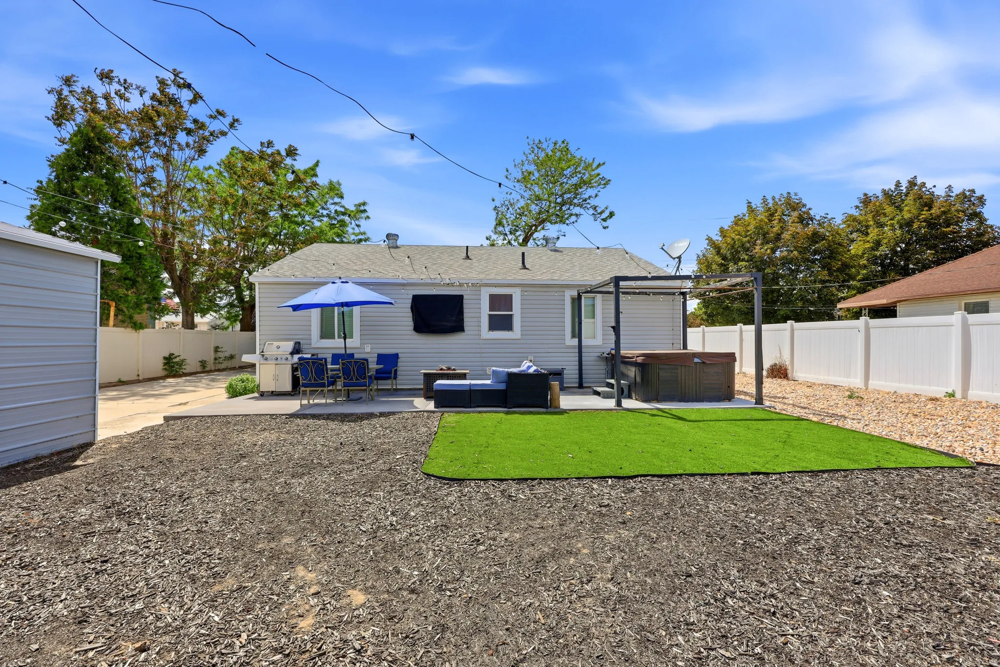 Backyard featuring a concrete patio, hot tub with pergola, artificial turf, and a privacy fence