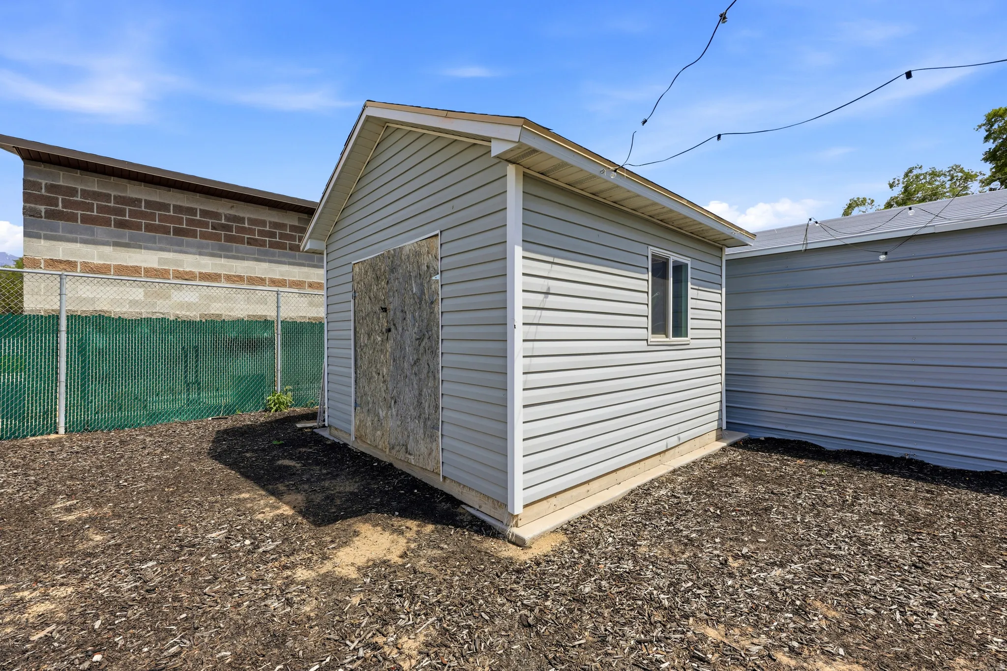 Detached shed featuring light gray vinyl siding and a single window