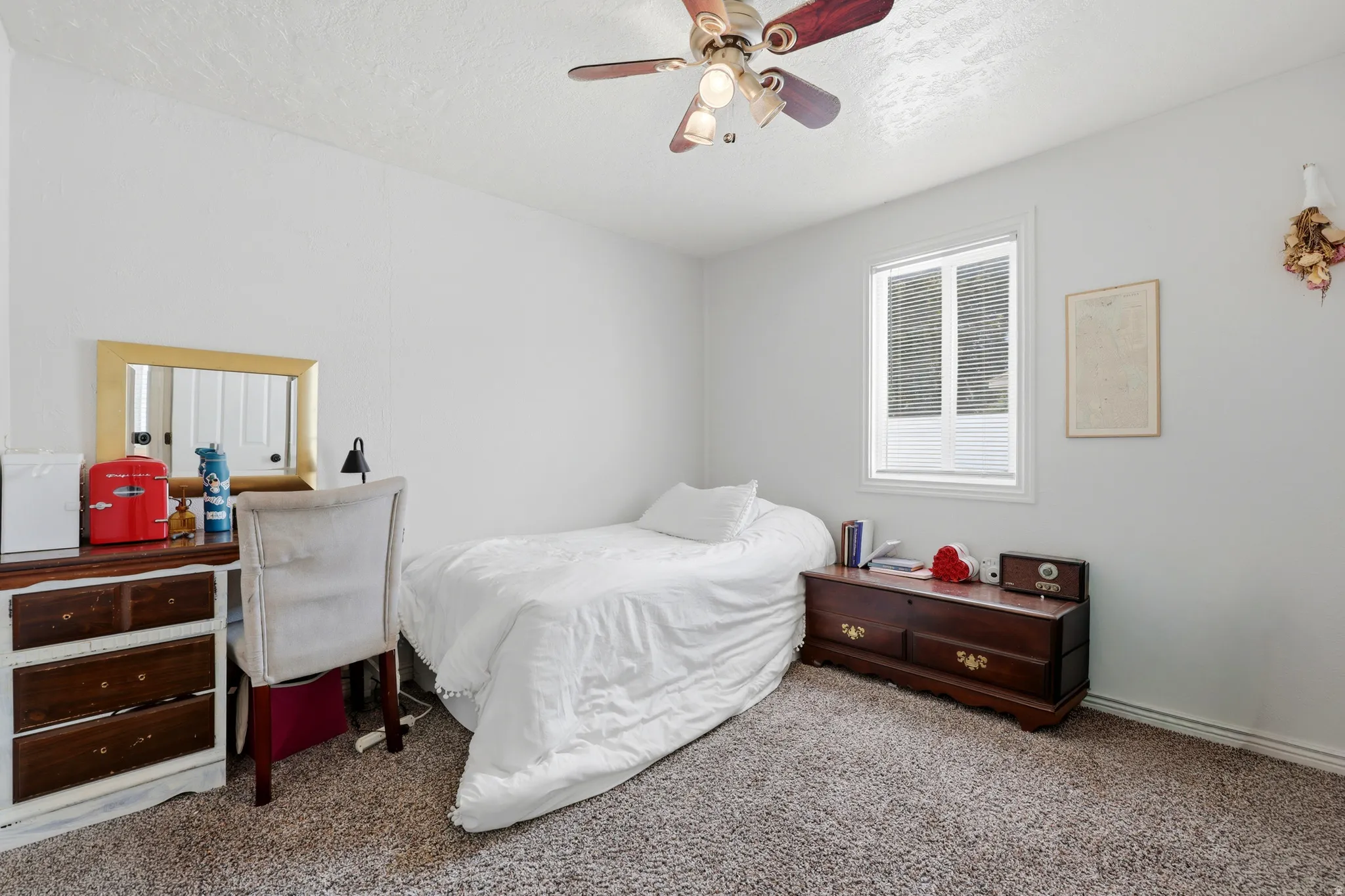 Light-filled room featuring neutral wall paint, a ceiling fan with integrated lighting, a window with blinds, and textured carpeting