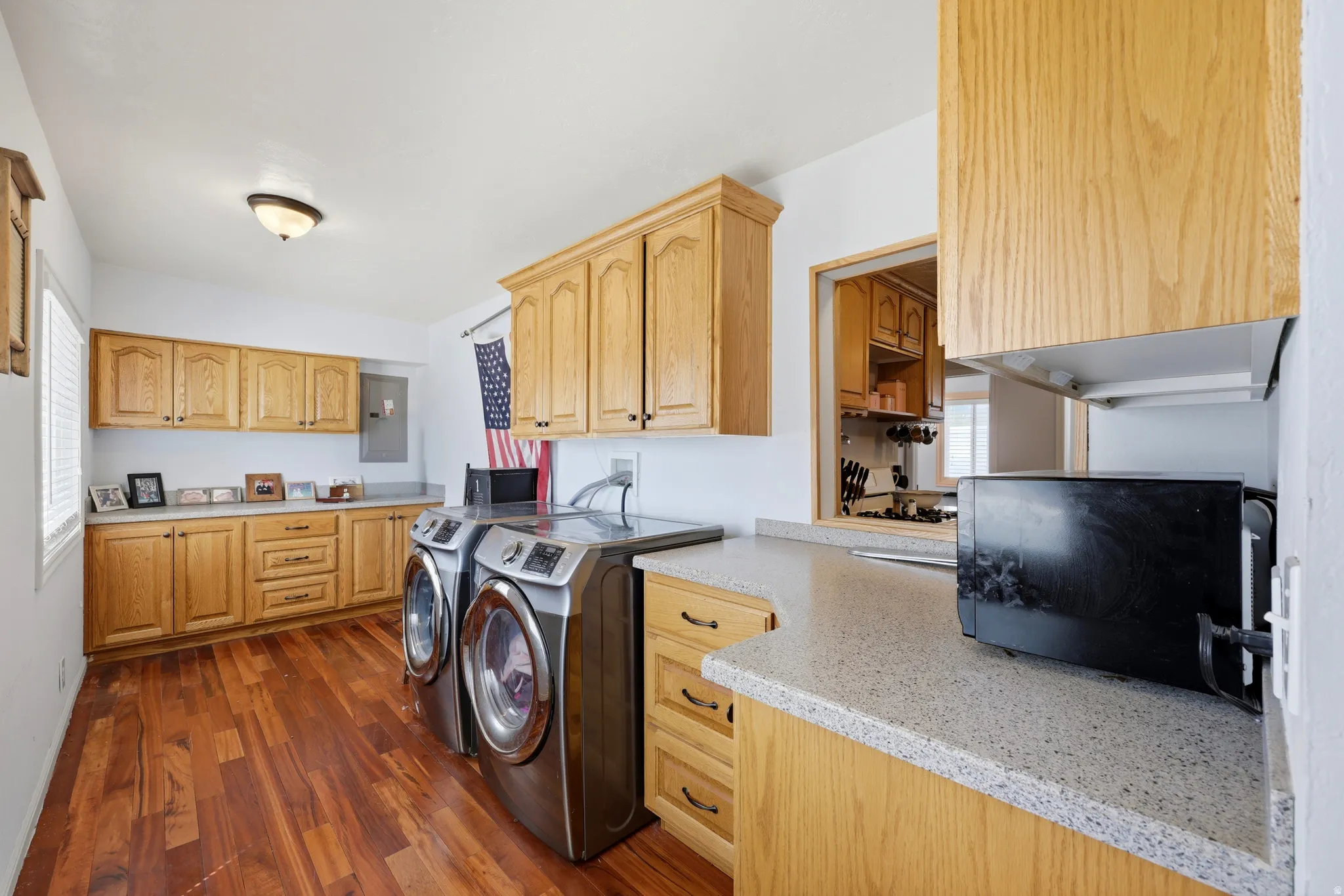 Laundry room featuring wood-finish flooring, ample cabinetry, and light-toned countertops