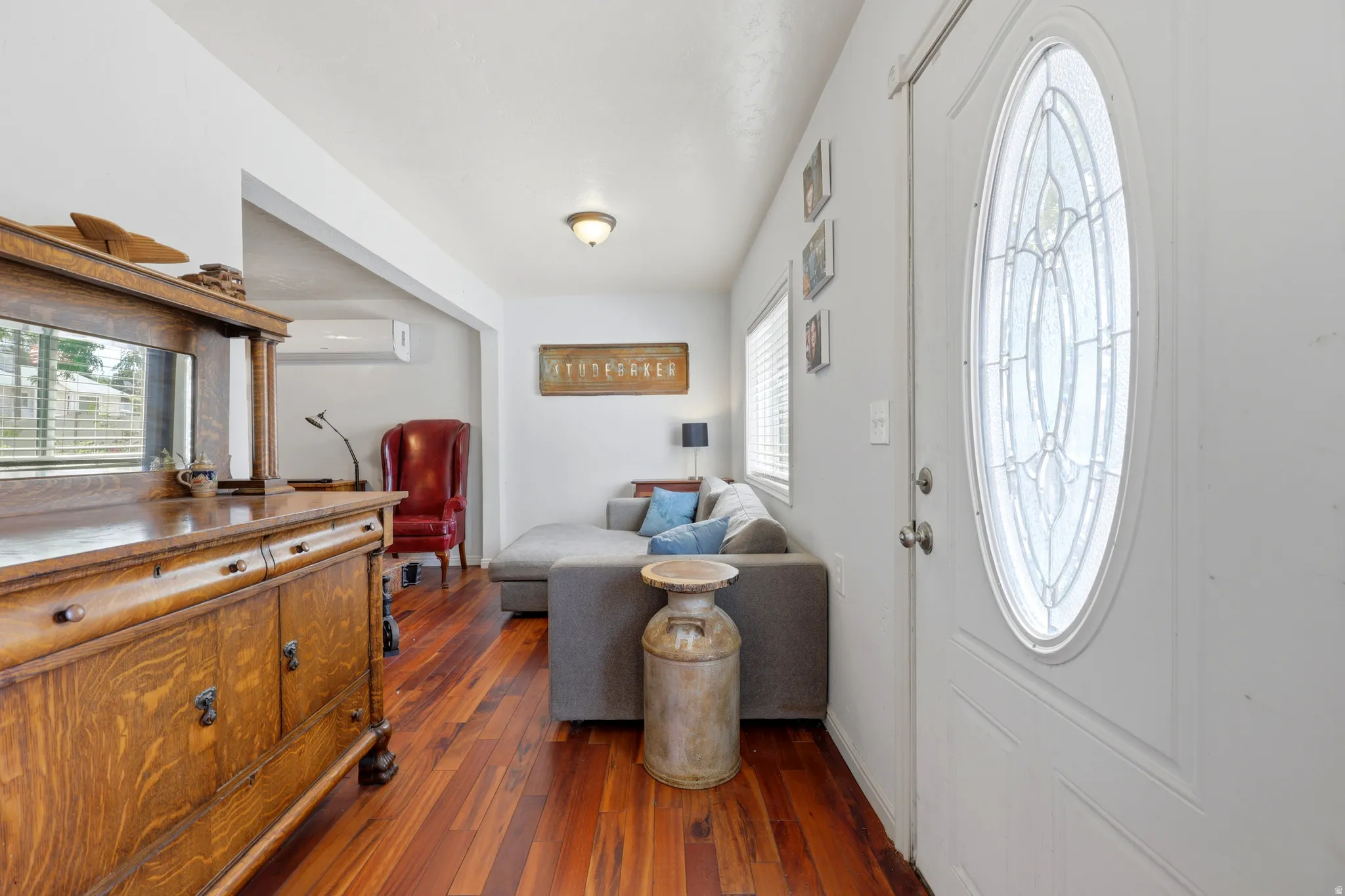 Entryway featuring a white door with an oval decorative glass insert, rich wood-finish flooring, and white walls