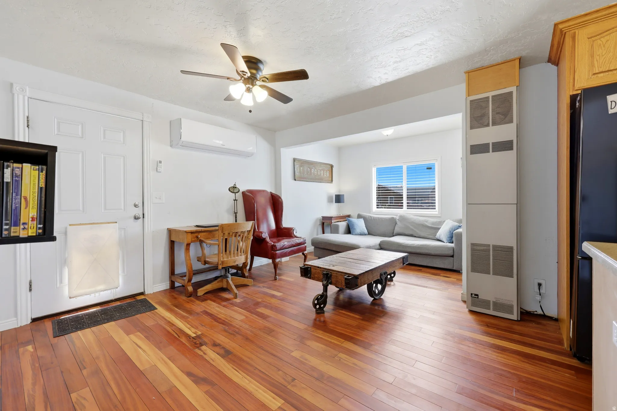 Open concept living area featuring wood-finish flooring, a ceiling fan, and a mini-split system