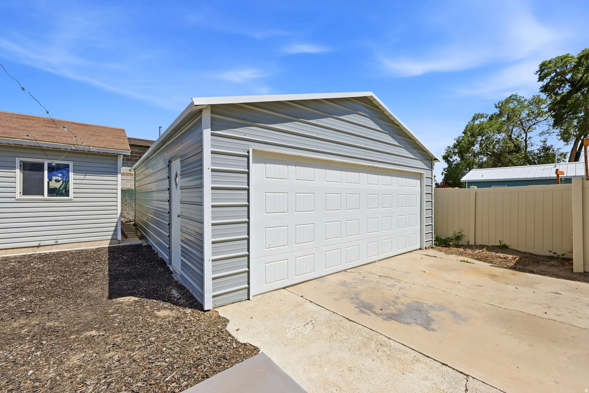 Detached metal garage featuring a white panel door and an additional side entrance