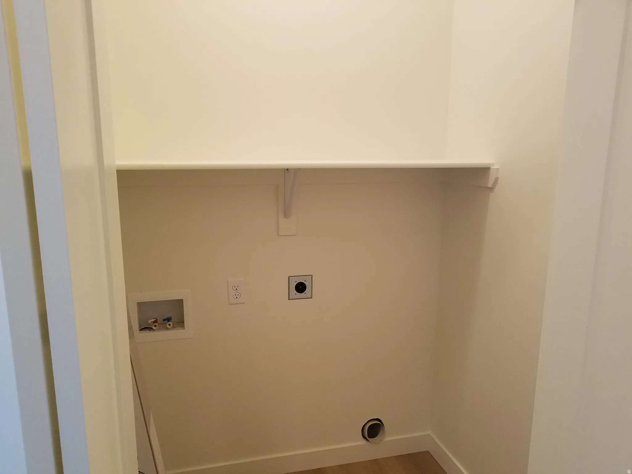 Dedicated laundry area featuring a built-in shelf, washer hookups, dryer vent, and electrical outlet