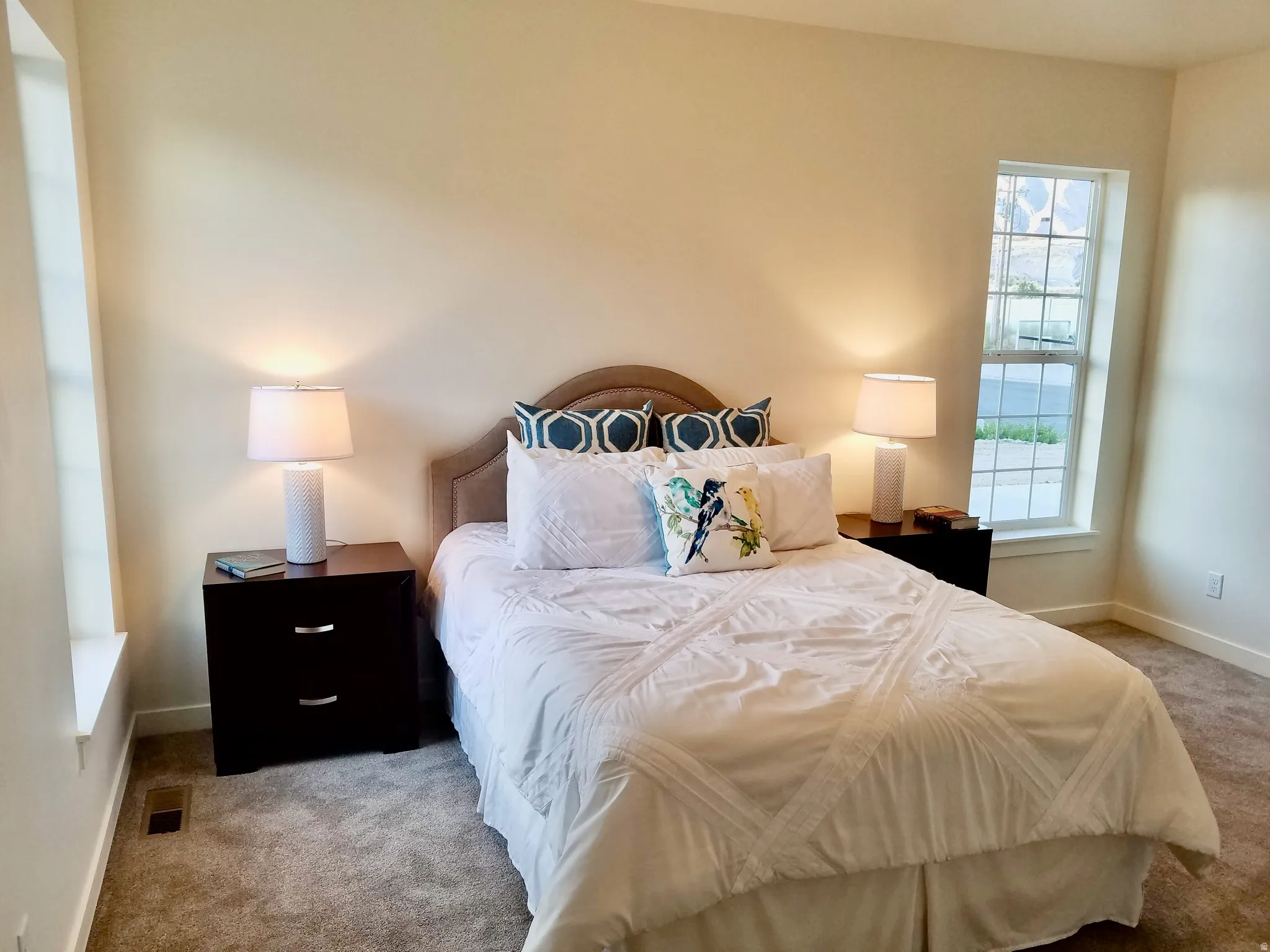 Carpeted room with a bed featuring a fabric upholstered headboard