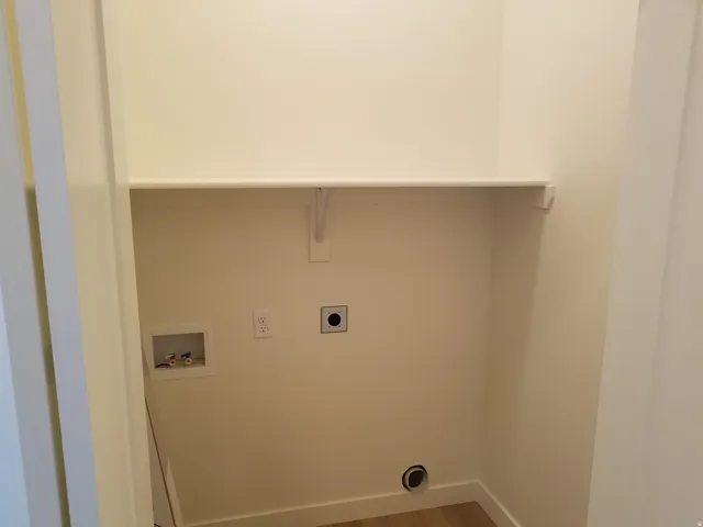 Dedicated laundry area featuring a built-in shelf, washer hookups, dryer vent, and electrical outlet