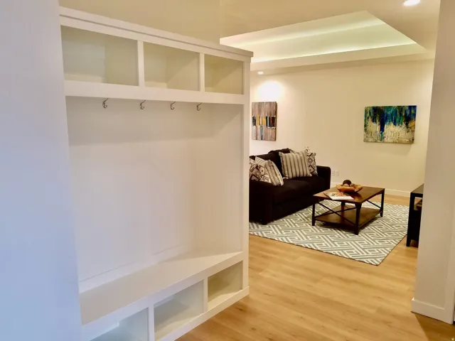 Built-in storage with upper shelving and coat hooks, complemented by recessed lighting and wood-finish flooring