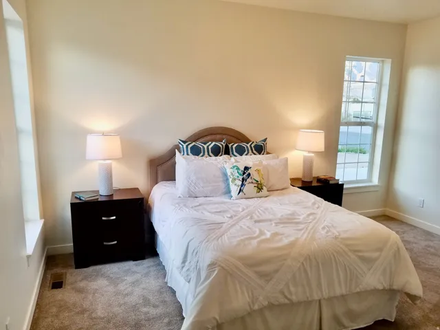 Carpeted room with a bed featuring a fabric upholstered headboard