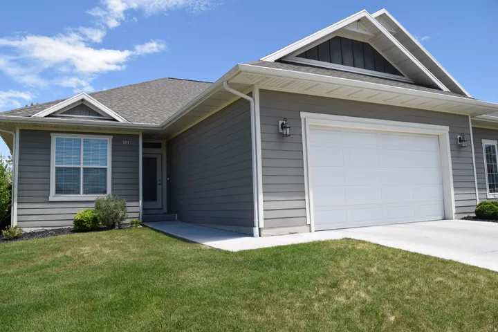 Contemporary facade featuring horizontal siding, a white sectional garage door, and a gabled roofline