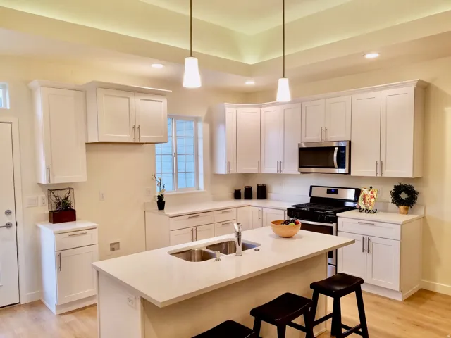 Modern kitchen featuring white shaker cabinetry and light-toned wood-finish flooring