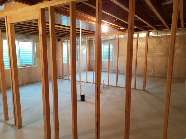 Unfinished basement with exposed wooden framing and concrete flooring