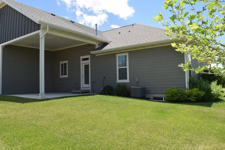 Expansive backyard featuring a covered patio, manicured lawn, and mature landscaping