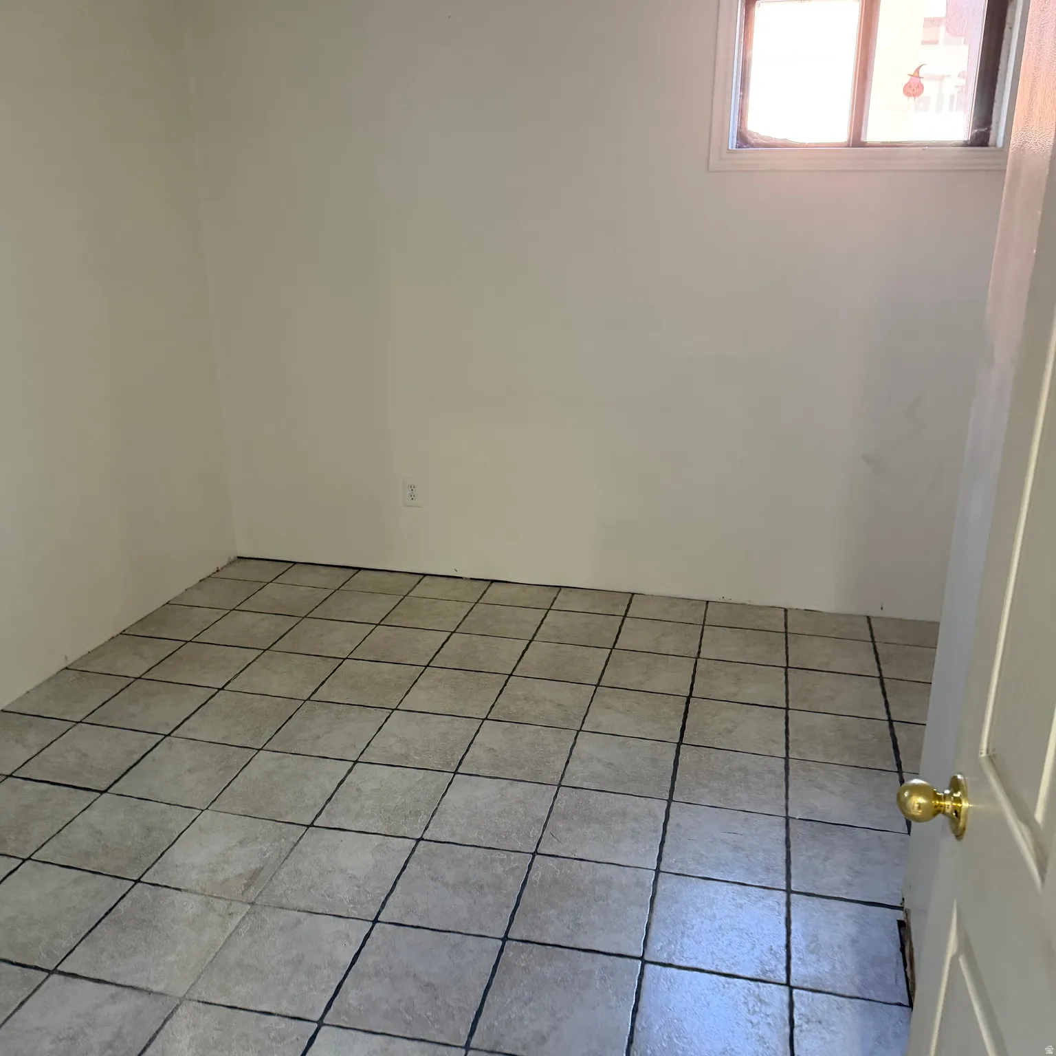 Room featuring neutral-toned tile flooring, white painted walls, and a window with white trim