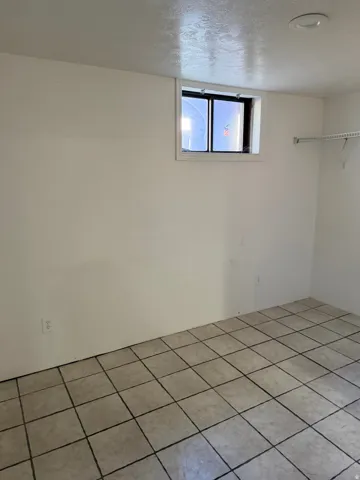 Tiled flooring, small window, white walls, and overhead lighting