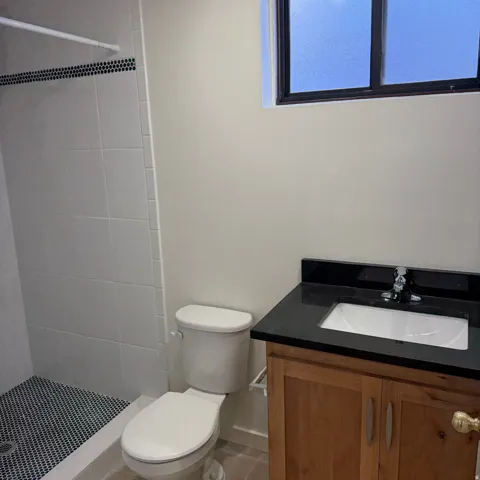 Bathroom featuring a vanity with a wood-finish cabinet, a black countertop, and an integrated sink
