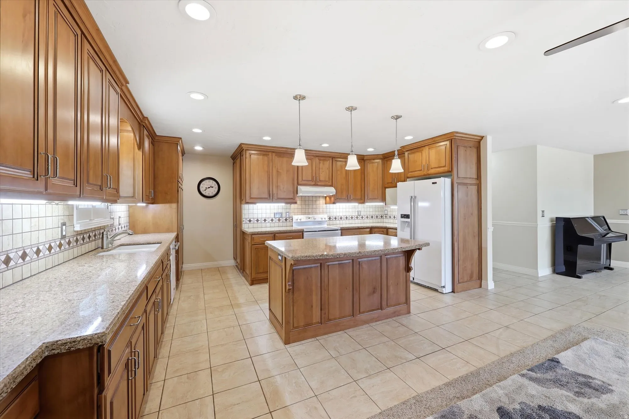 Expansive kitchen featuring wood cabinetry, light-toned countertops, and a tiled backsplash