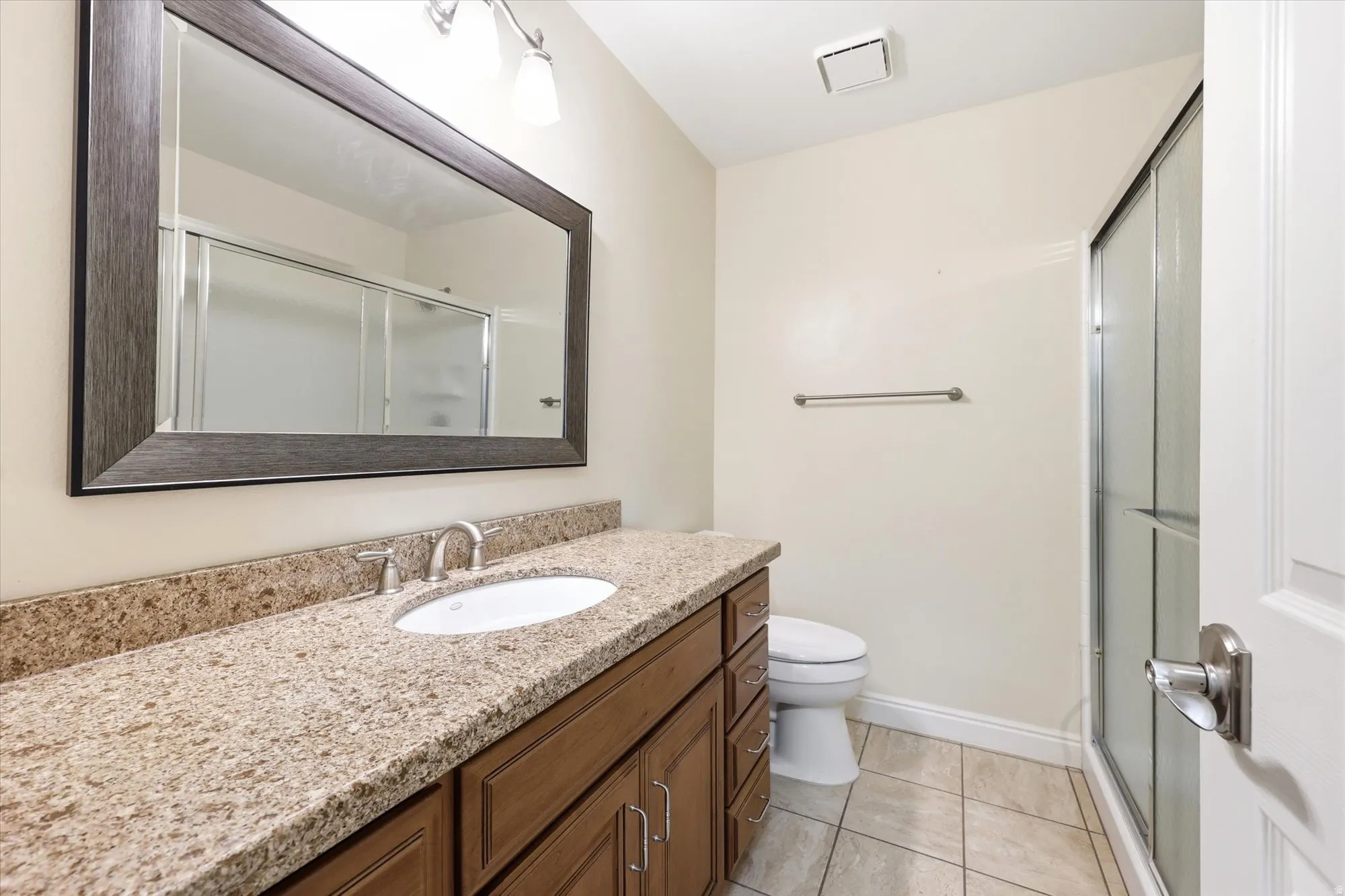 Bathroom vanity featuring a light-toned countertop, an undermount sink, and a brushed nickel faucet