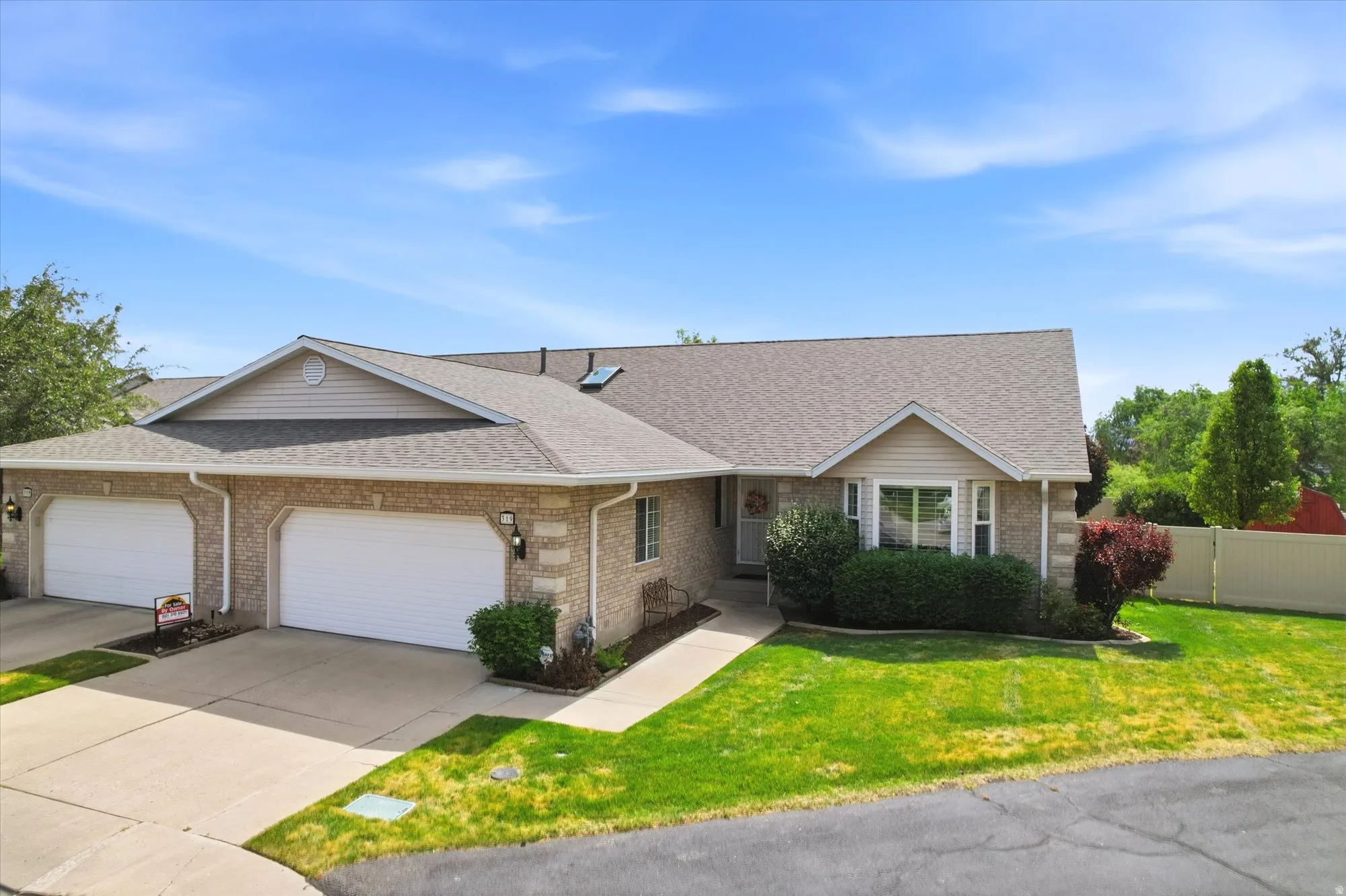 Brick and siding exterior featuring a multi-car driveway, attached garages with white doors, a front walkway, and mature landscaping