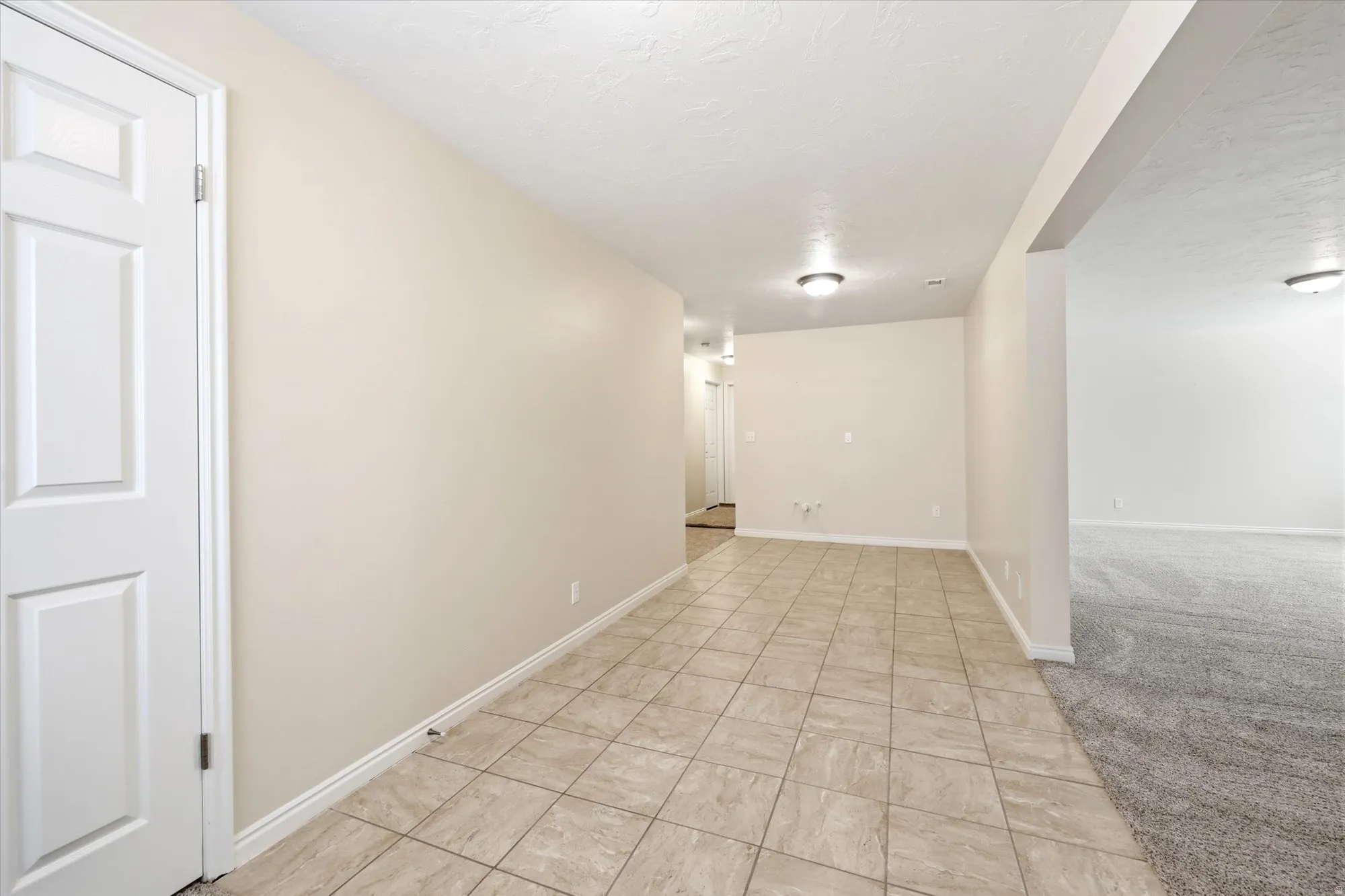Tiled entry area featuring warm neutral wall tones and white baseboards