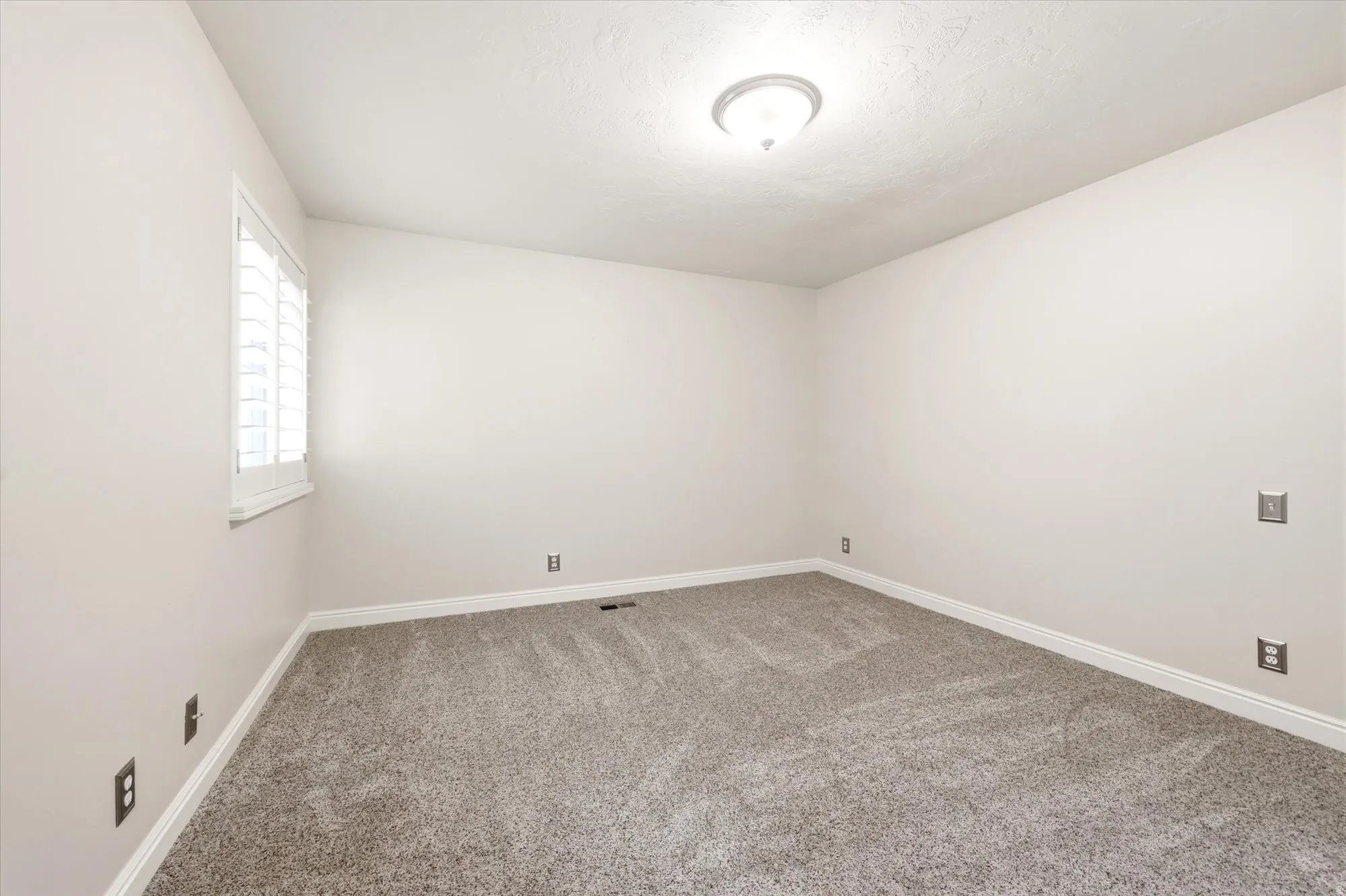 Neutral-toned walls complement the plush gray carpeting