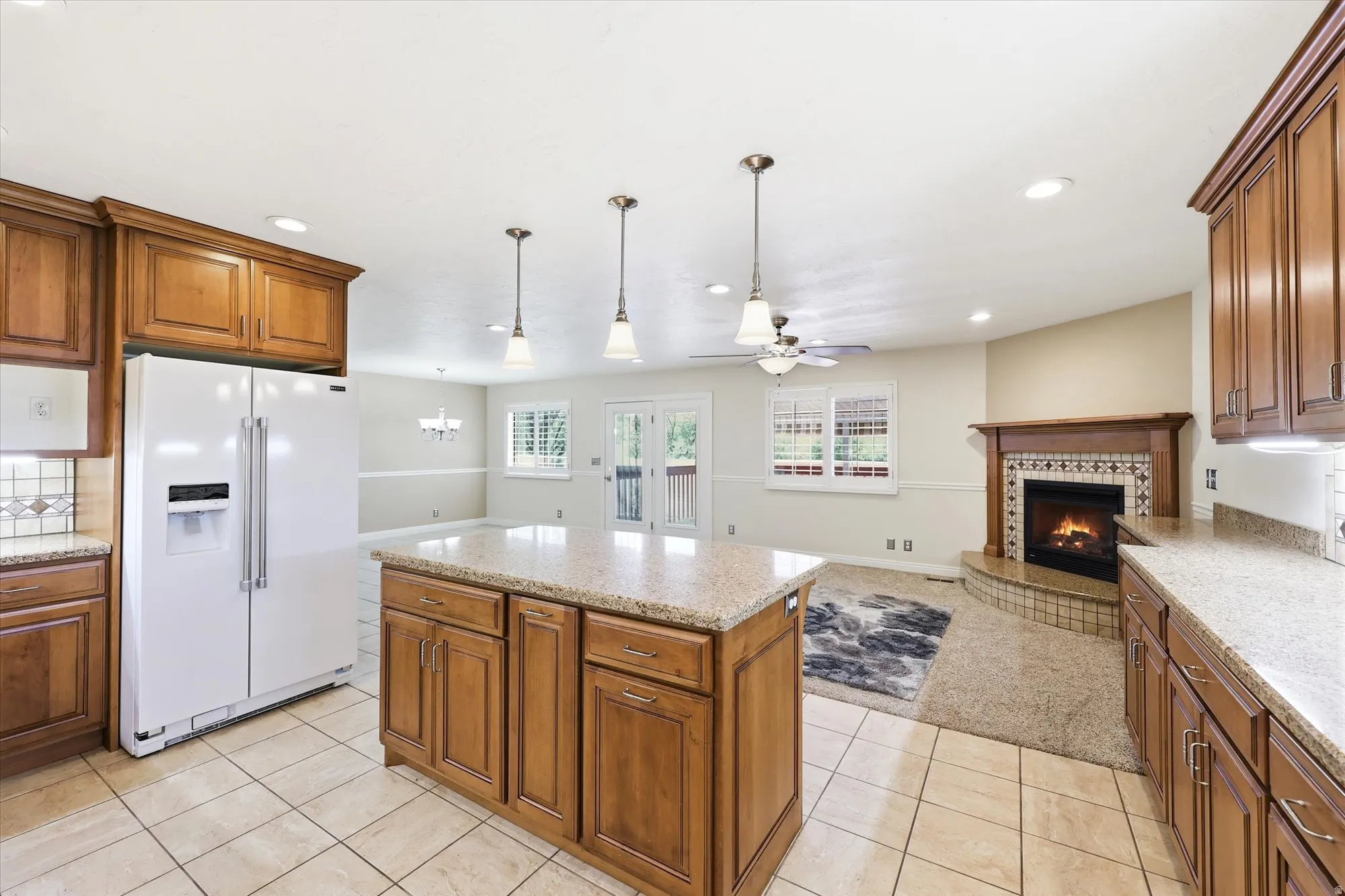 Kitchen with wood cabinetry, light-toned tile flooring, and granite countertops