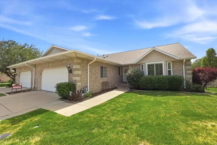 Brick exterior featuring two white garage doors and an additional front entry