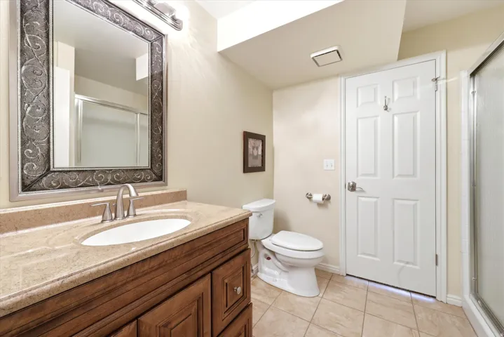 Bathroom featuring a wood-finish vanity with a built-in sink and light-toned countertop