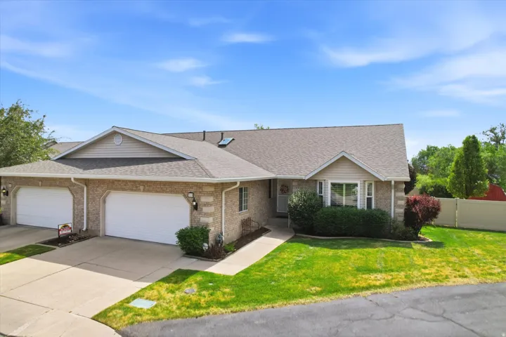 Brick and siding exterior featuring a multi-car driveway, attached garages with white doors, a front walkway, and mature landscaping