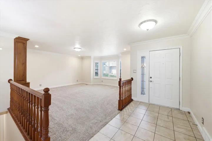 Entryway featuring a white paneled door with decorative glass sidelite, light-toned ceramic tile flooring, and a coordinating overhead light fixture