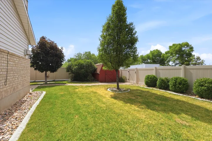 Expansive green lawn with mature trees and a red shed