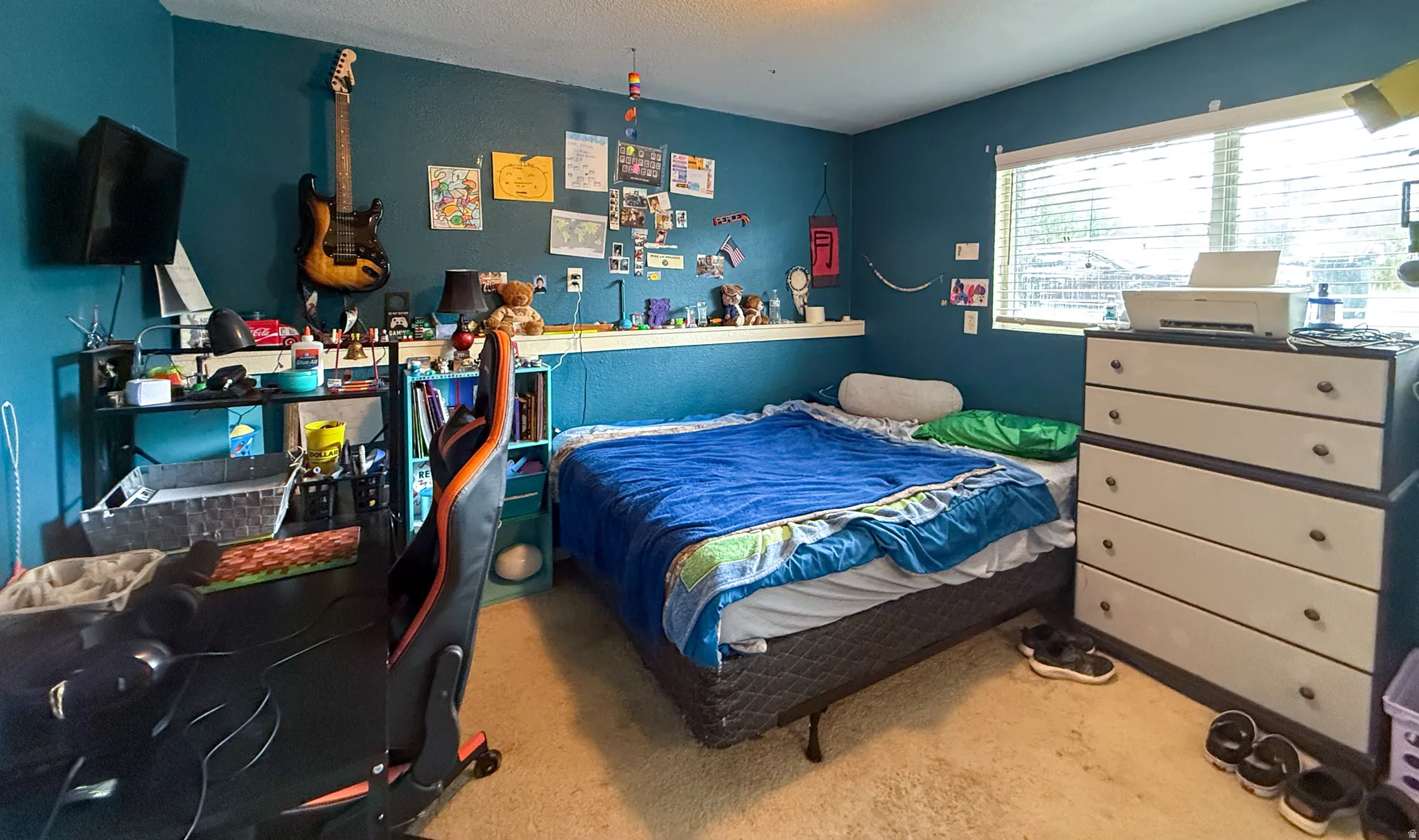 Room featuring a large window with blinds, a built-in floating shelf, and neutral-toned carpeting