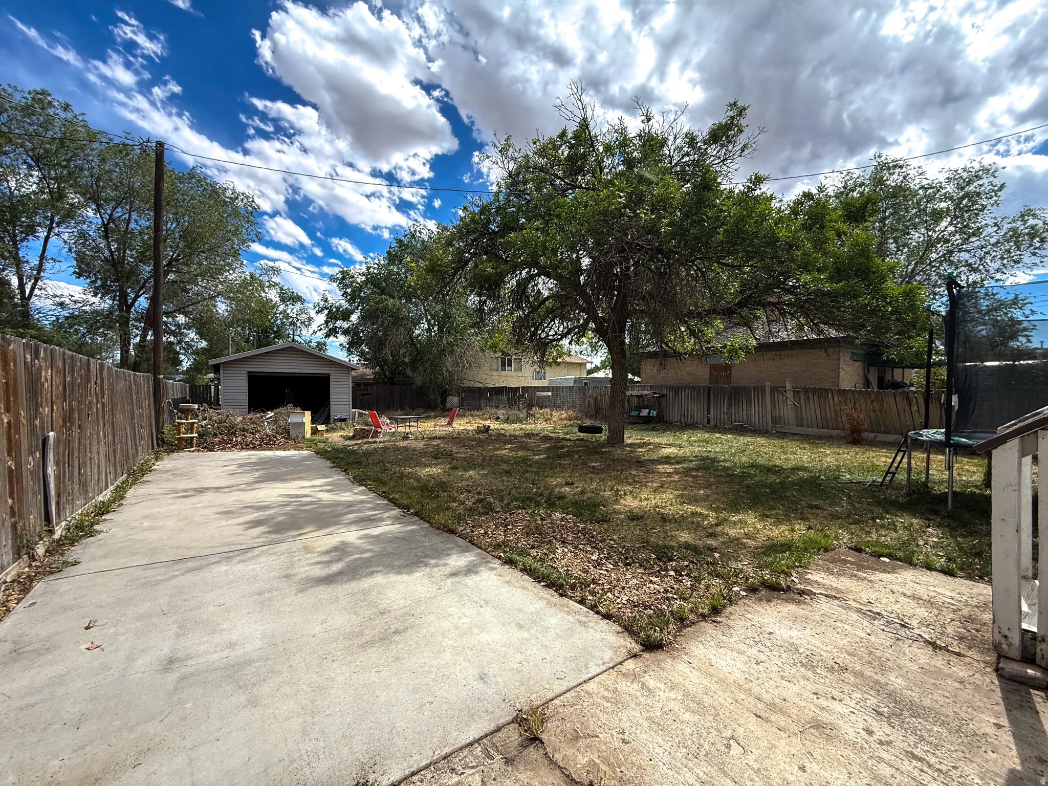 Expansive backyard featuring a mature tree, wood fencing, and a detached garage with a roll-up door