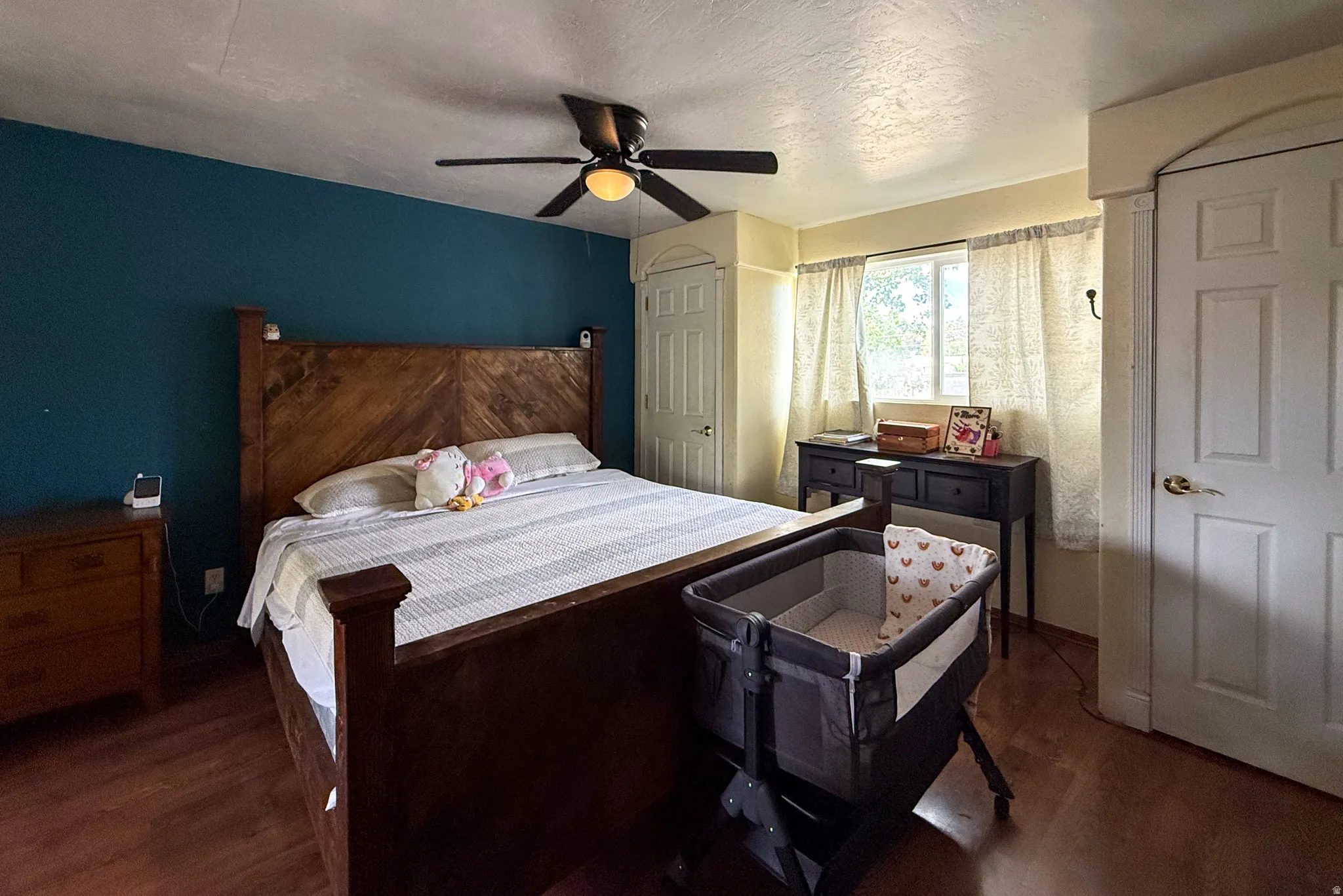 Spacious room featuring wood-finish flooring, a ceiling fan with integrated lighting, and a window providing natural light