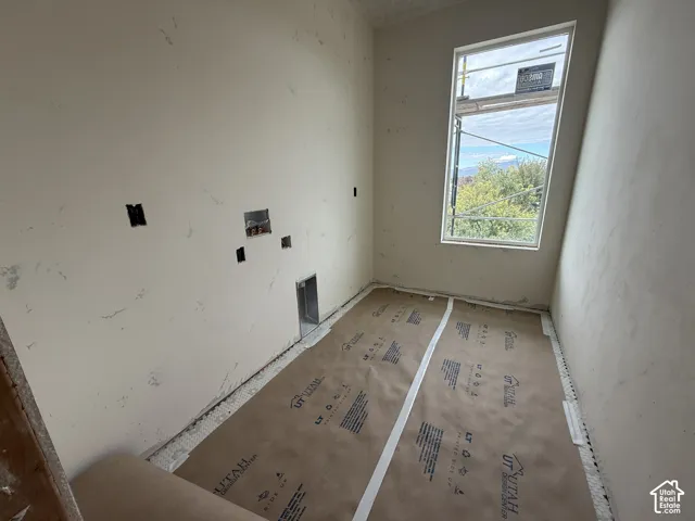 Unfinished room featuring drywall, a tall vertical window, and built-in utility hookups