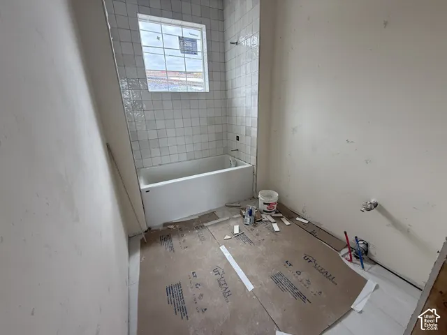 Full-height white square tile tub surround, integrated soaking tub, and window with grid muntins
