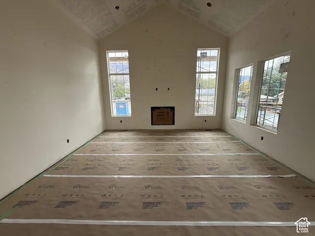 Vaulted ceilings featuring a central fireplace and expansive windows
